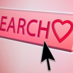 Cursor hovers over a search button with a heart symbol on it - online internet dating / love concept